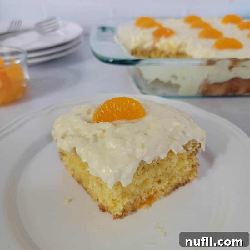 A square slice of festive Pig Pickin’ Cake on a white plate, positioned in front of the full baking dish and a stack of plates.