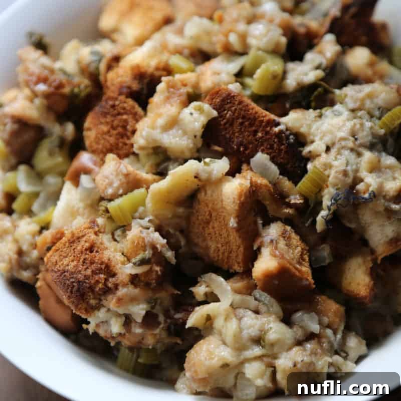 A white bowl brimming with homemade CrockPot Stuffing, featuring golden-brown bread pieces and tender celery, a perfect holiday accompaniment.
