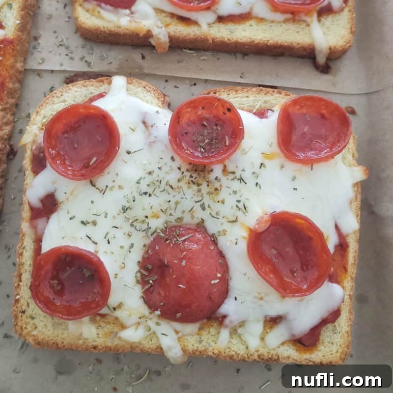 A delicious slice of pepperoni pizza toast resting on parchment paper, bubbling with melted cheese and savory pepperoni, ready for a quick snack or light meal.