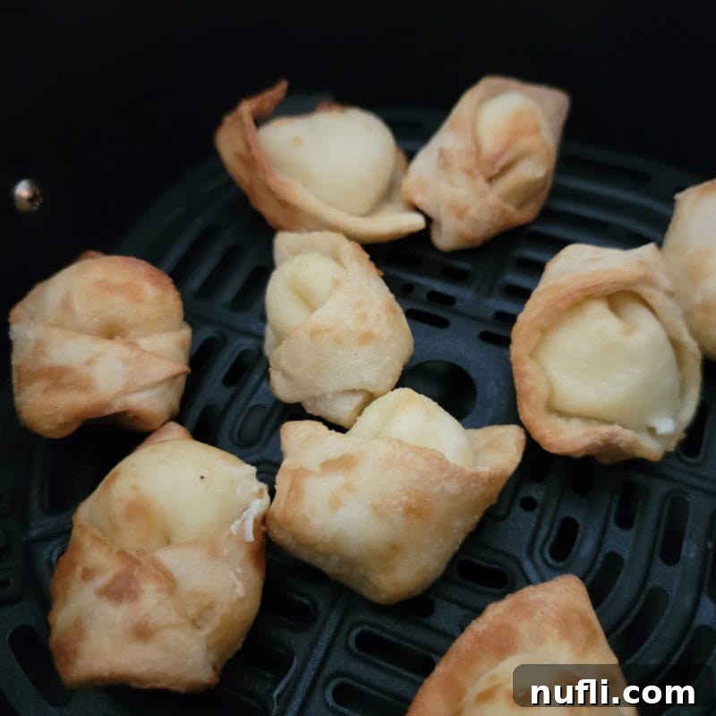 Crispy air-fried cream cheese wontons, golden and beautifully arranged in an air fryer basket, ready to be served.
