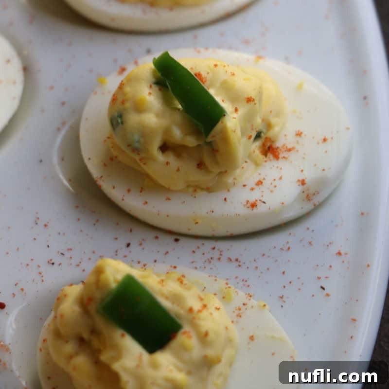 Elegant spicy deviled eggs, beautifully garnished and arranged on a decorative egg platter, showcasing their vibrant color and inviting kick.