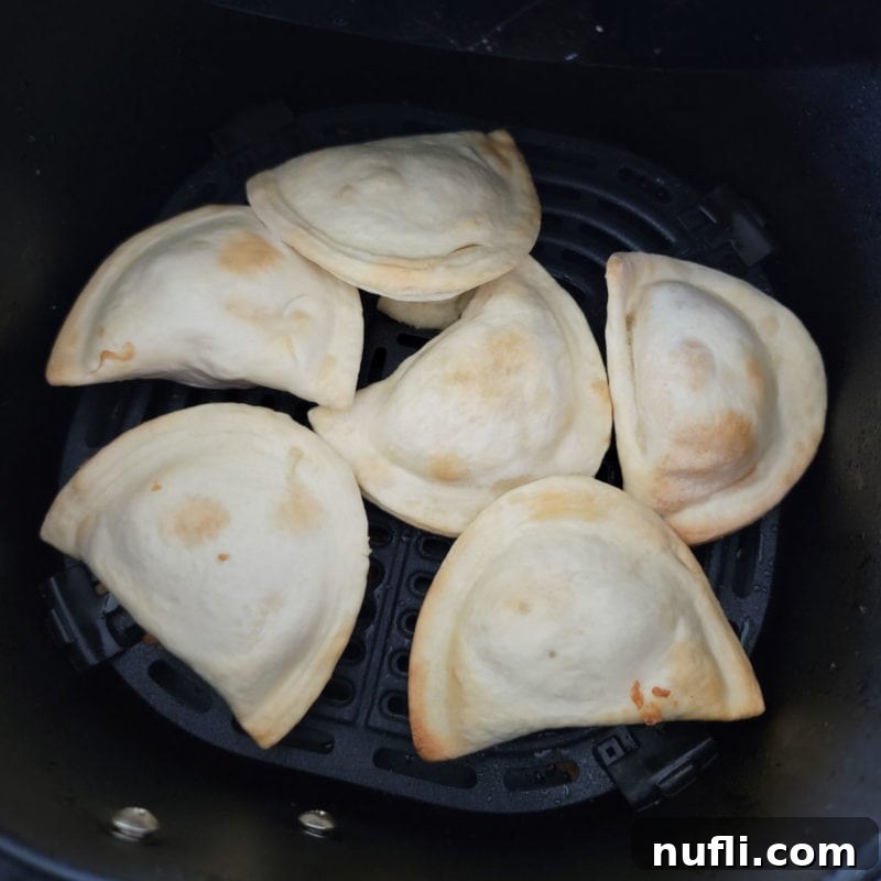 Perfectly air-fried pierogies cooking to a golden crisp in an air fryer basket, ready to be served.