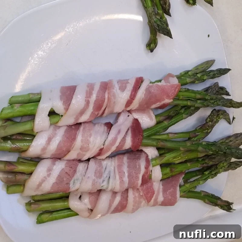 Bacon Wrapped Asparagus on a white plate before cooking