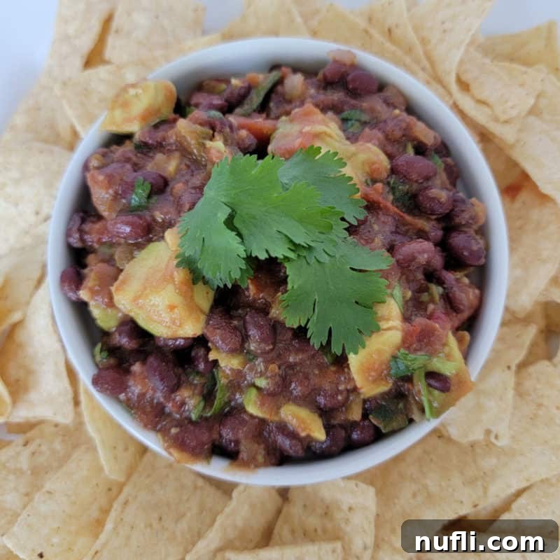 Black bean salsa in a white bowl surrounded by tortilla chips