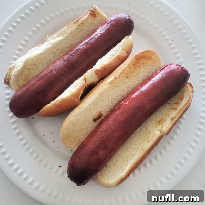 Over 30 Essential Sides for Burger Enthusiasts 11 Two perfectly air-fried hot dogs nestled in toasted buns on a white plate, ready for a delicious meal.