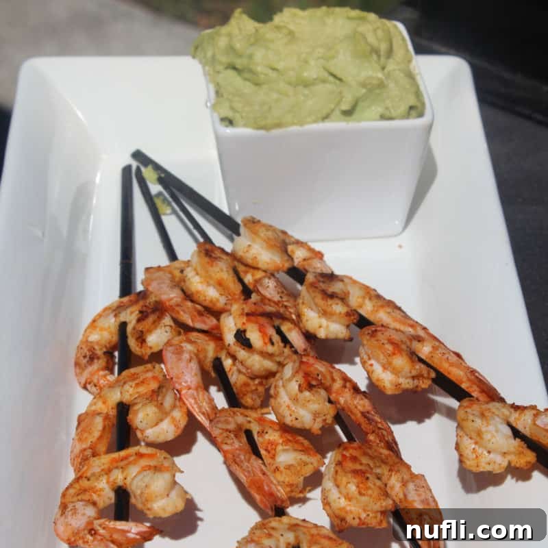 Over 30 Essential Sides for Burger Enthusiasts 17 Delicious grilled shrimp skewers served in front of a bowl of creamy avocado butter, creating an elegant surf-and-turf burger side.