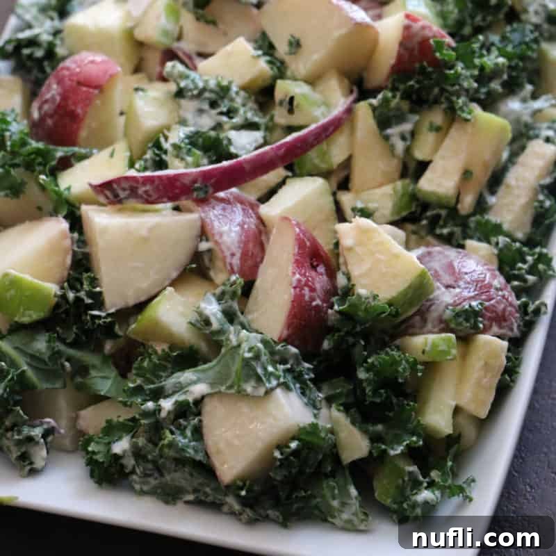 Over 30 Essential Sides for Burger Enthusiasts 19 A unique Kale and Apple Potato Salad arranged on a white platter, showcasing fresh ingredients and a healthy twist on a classic.