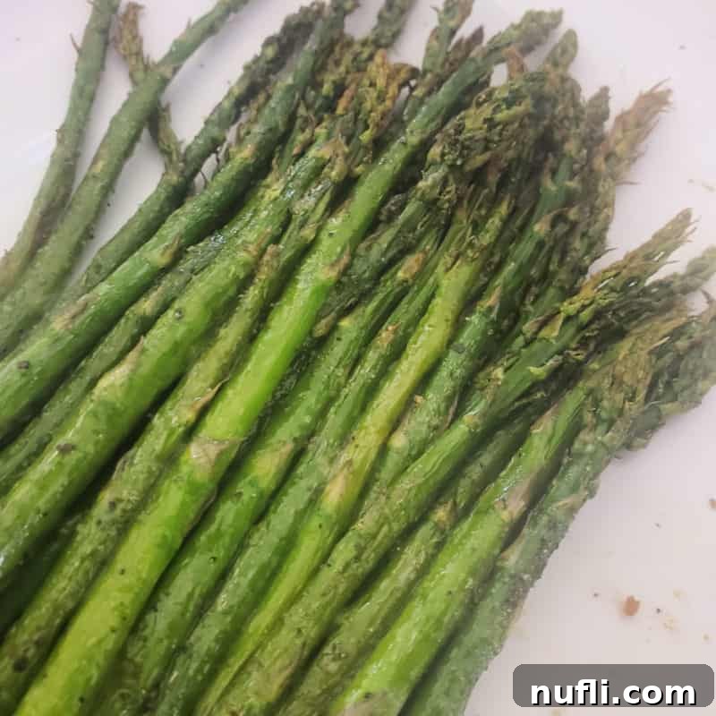 Over 30 Essential Sides for Burger Enthusiasts 26 Fresh, perfectly cooked asparagus spears arranged neatly on a white plate, ready to be served.