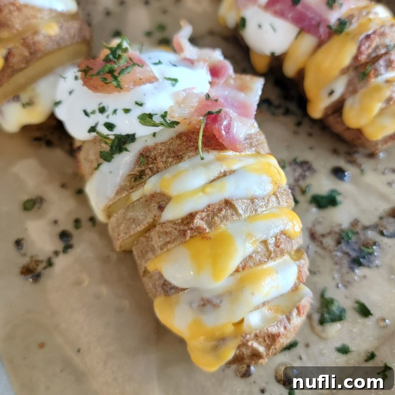 Over 30 Essential Sides for Burger Enthusiasts 7 A beautifully sliced Hasselback Potato resting on parchment paper, garnished with fresh herbs, ready to be served.