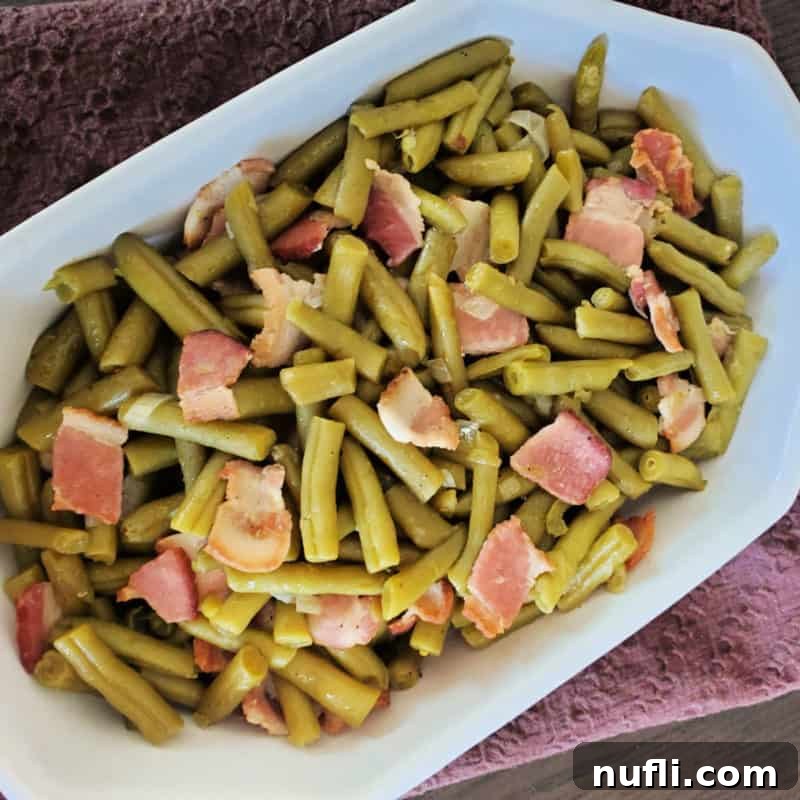 Over 30 Essential Sides for Burger Enthusiasts 9 Hearty Cracker Barrel Green Beans with savory bacon, served in a white dish, a comforting side for any meal.