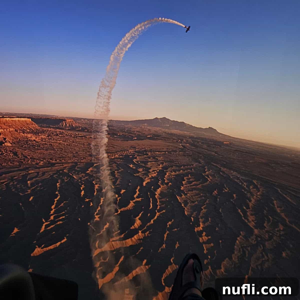 Plane with smoke trail flying over the American West. Feet in Birkenstock sandal at the bottom of the screen