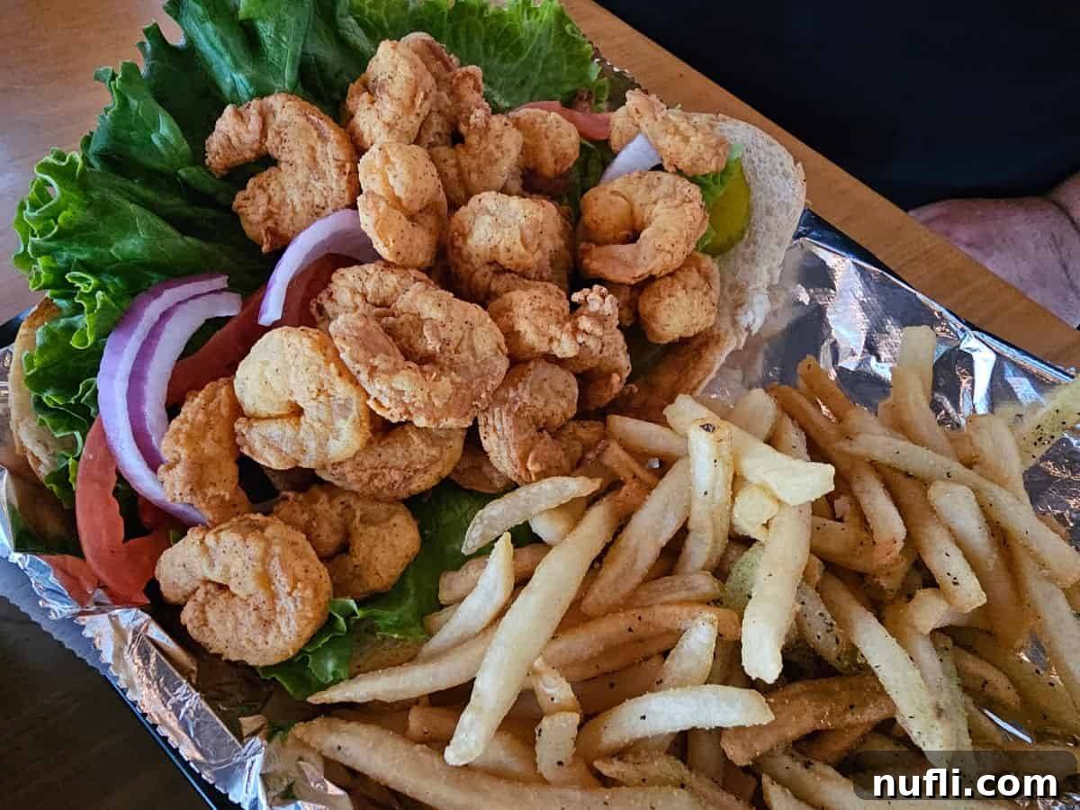Crispy fried shrimp po'boy served in a basket with golden fries, a classic Southern dish.