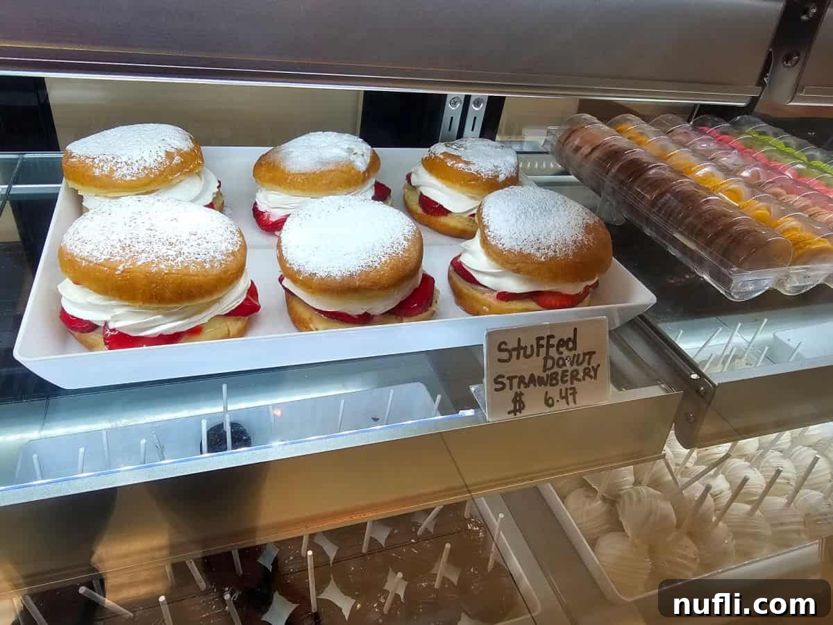 Tray of luscious stuffed strawberry donuts showcased in a bakery display case.