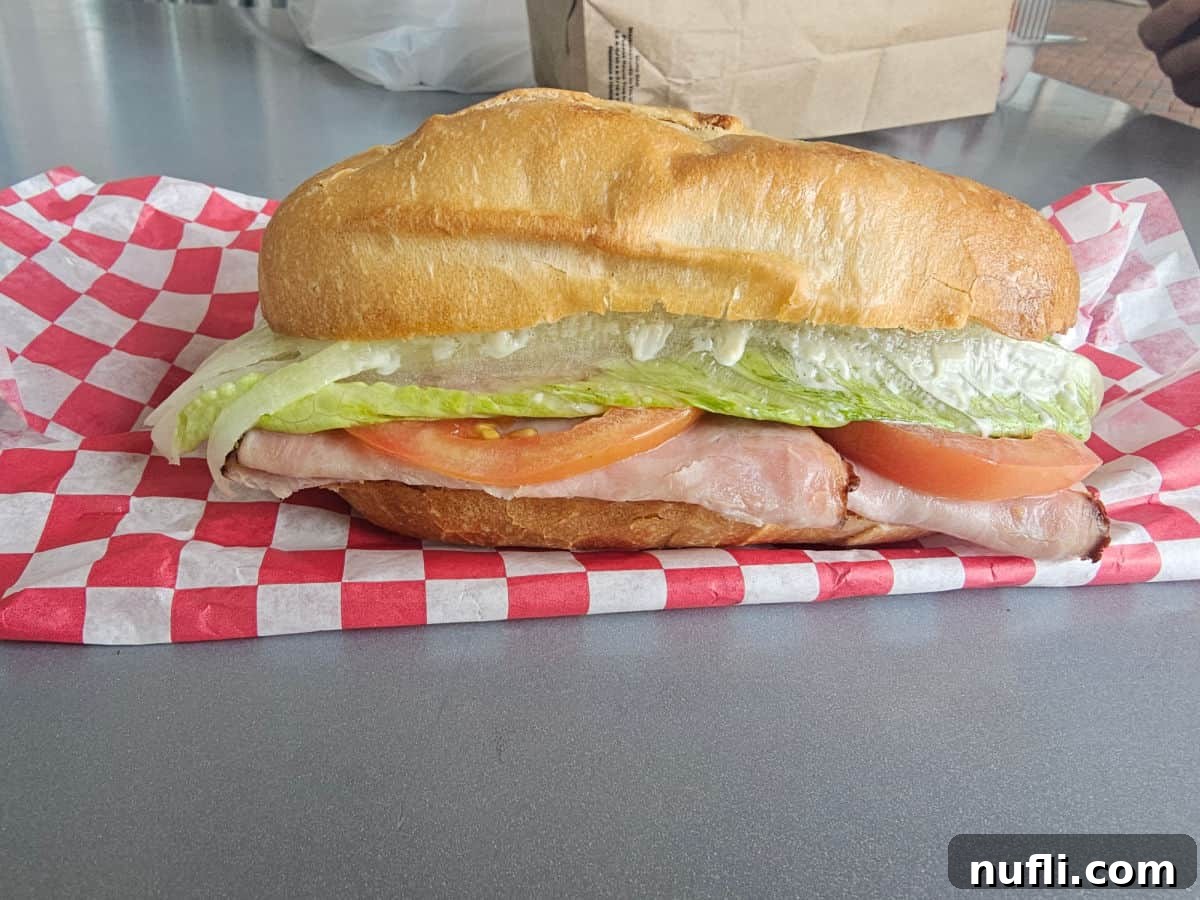 Hearty ham sandwich on red and white checkered paper liner, a perfect casual meal.
