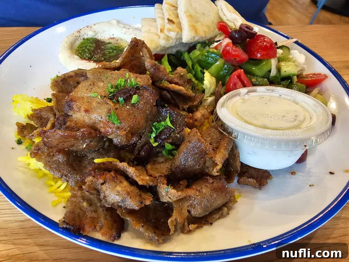 Delicious gyro plate with savory tzatziki sauce and warm pita bread pieces.