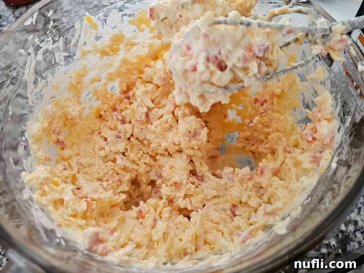 Pimento cheese in a glass bowl with mixer beaters at the edge of the bowl