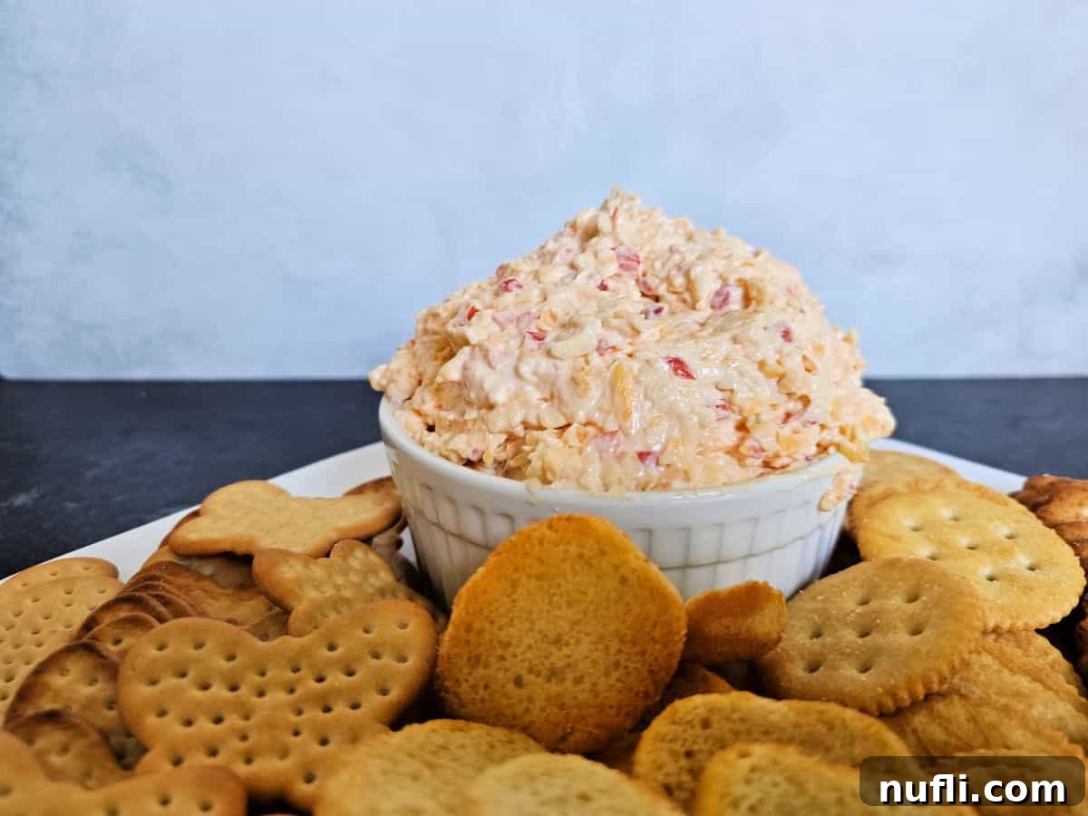 Pimenot cheese in a white bowl on a white platter filled with a variety of crackers