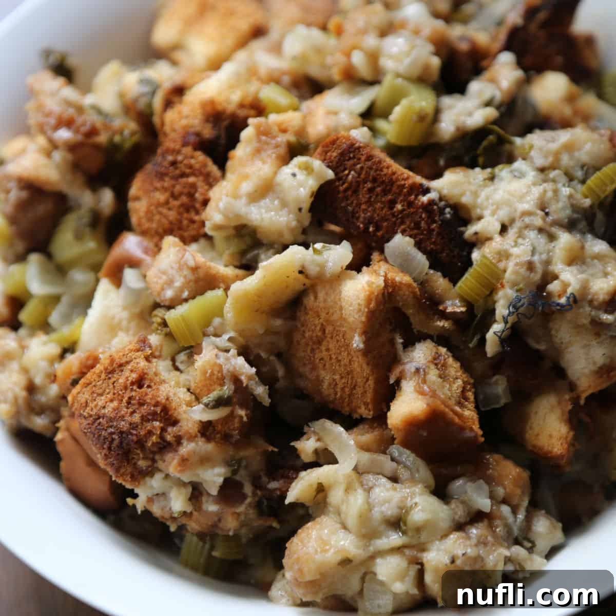 Savory Crockpot dressing with chunks of bread and celery in a white serving bowl, ready for a holiday meal.