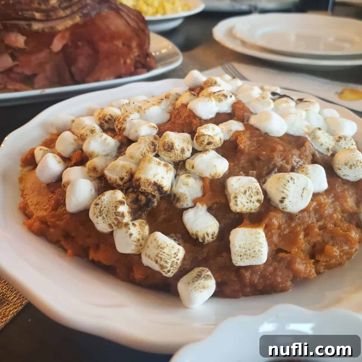 Golden CrockPot Sweet Potato Casserole topped with perfectly toasted mini marshmallows, served in a white bowl, a holiday classic.
