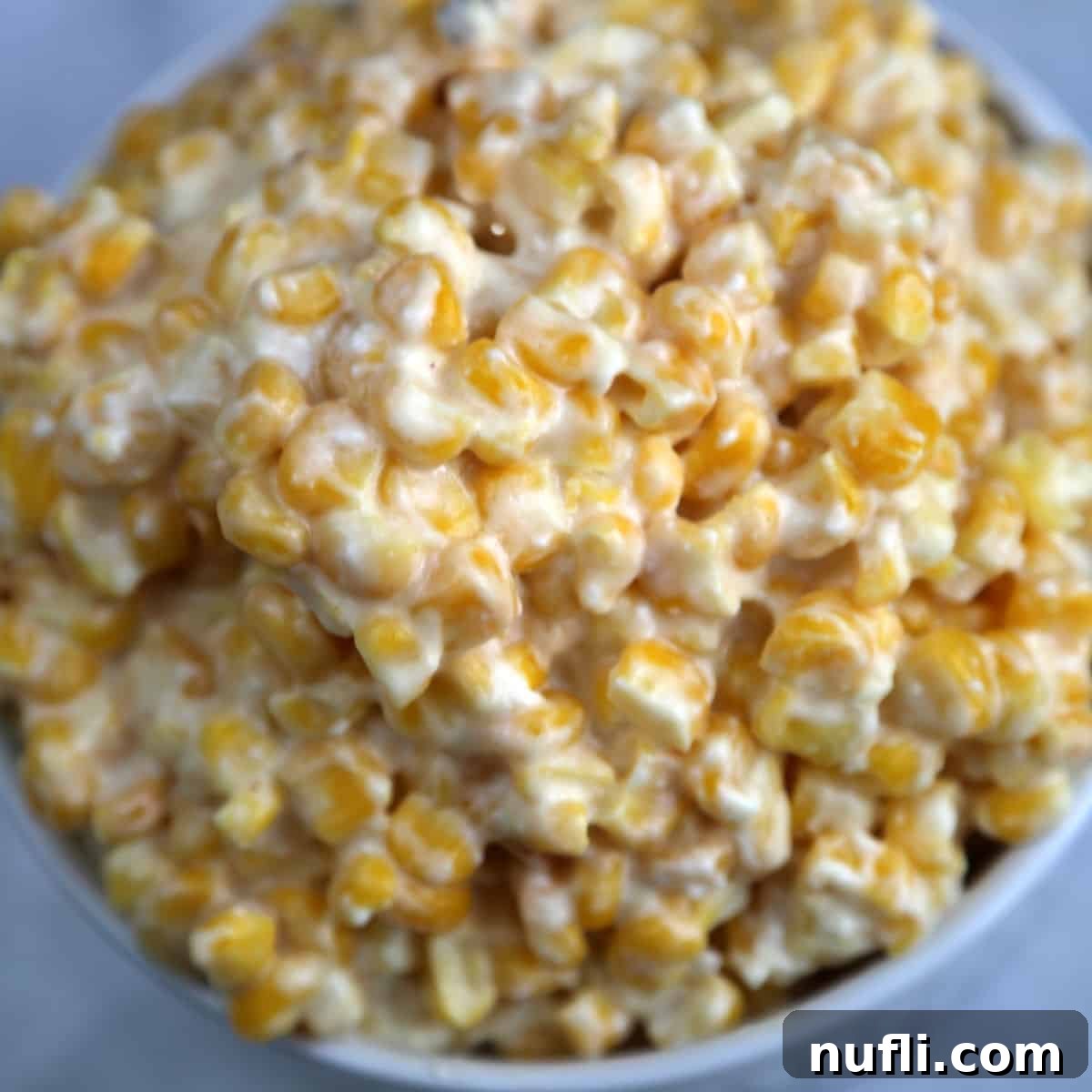 Creamy CrockPot Creamed Corn, a classic comforting side dish, served in a pristine white bowl.