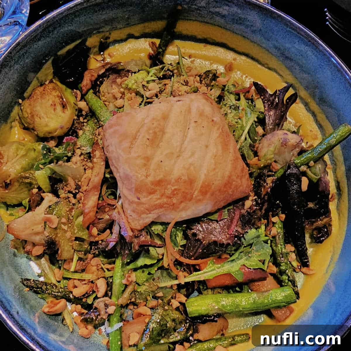 A beautifully presented goat cheese encroute, centrally placed in a bowl and surrounded by vibrant fresh vegetables