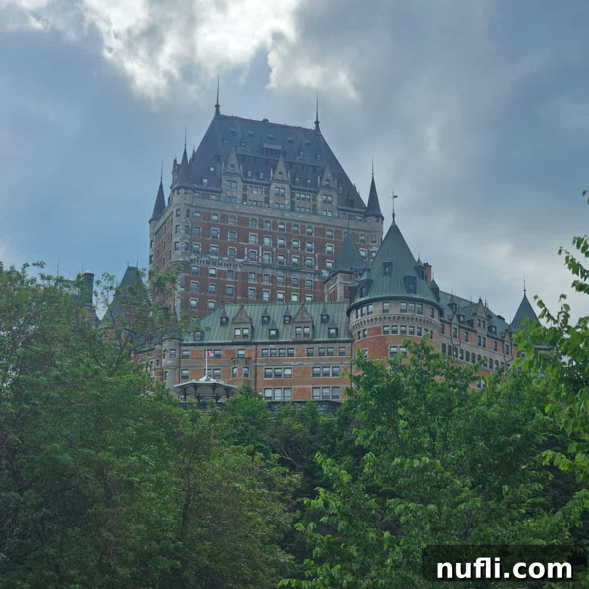 The iconic Fairmont Le Château Frontenac majestically perched on a hill, overlooking a canopy of trees and the city below