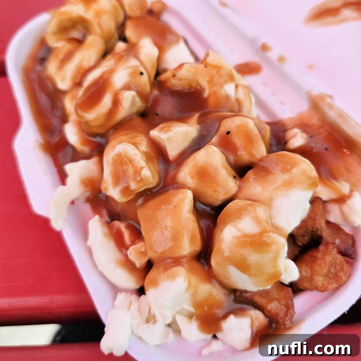 A container filled with fresh, squeaky cheese curds resting on a vibrant red table, ready for delicious poutine