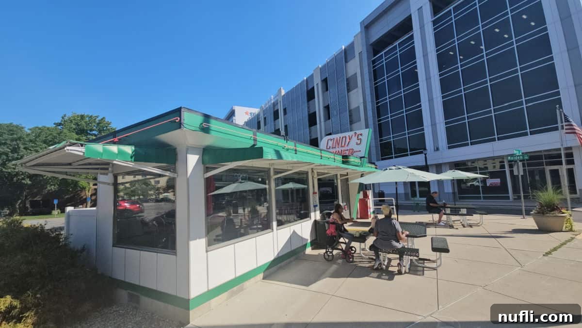 Cindy's Diner sign over the exterior of a white and green building with tables with green umbrellas outside