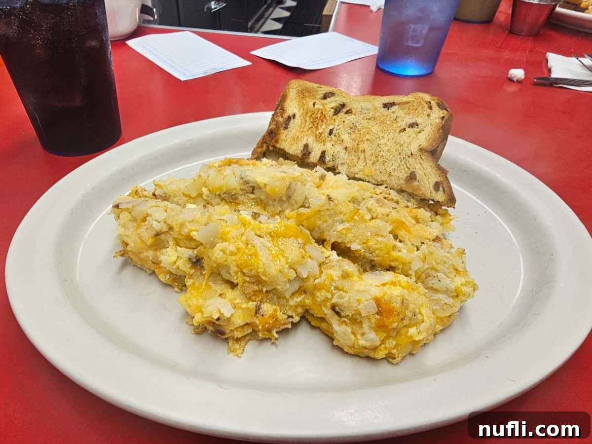 White plate with egg and hashbrown mix and raisin toast next to a diet coke