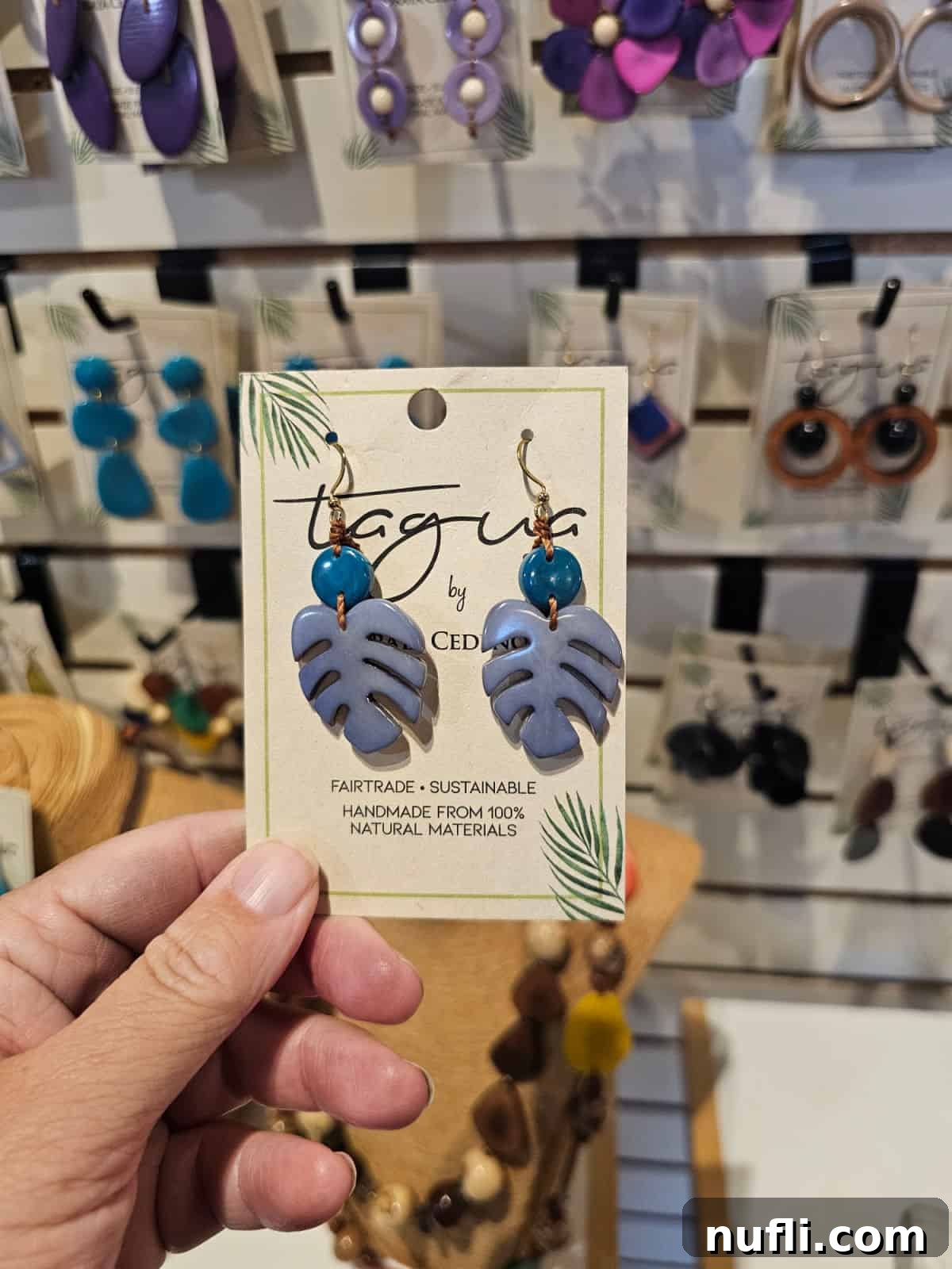 hand holding blue monstera leaf earings