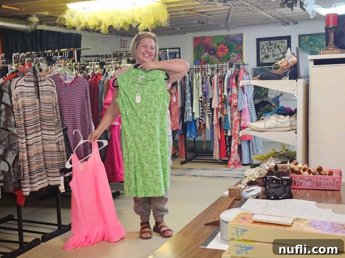Kin holding a green dress and a pink dress in easy tiger vintage store