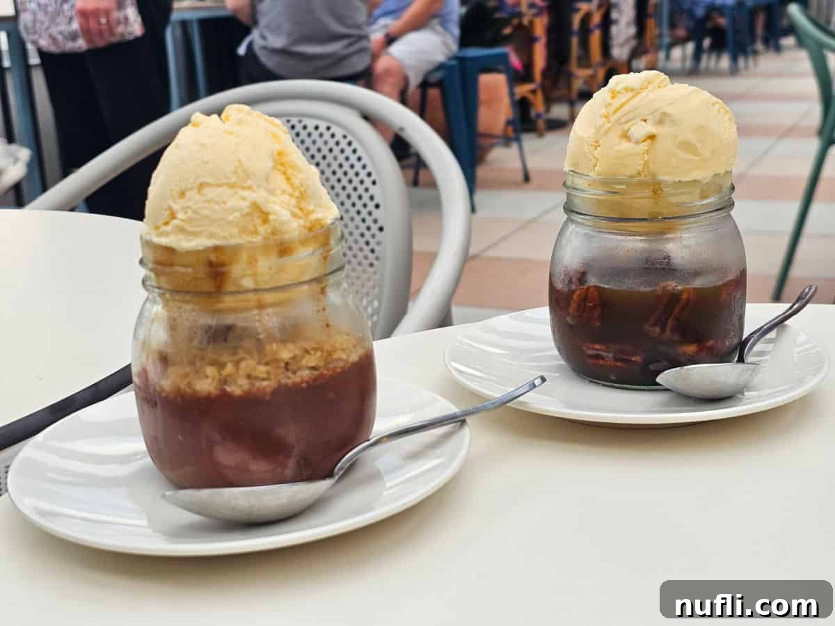 Cobblers in jars on white plates with scoops of vanilla ice cream on top