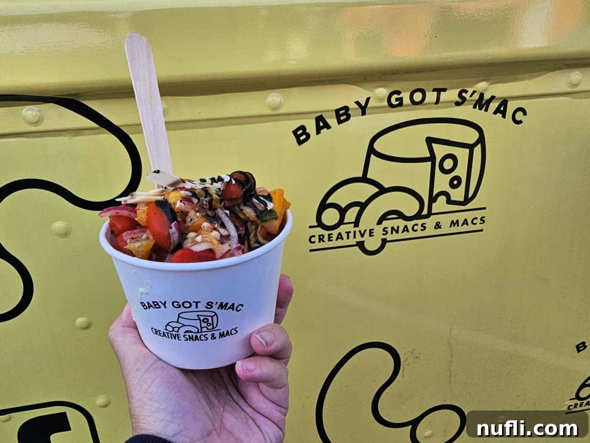 hand holding a cup of Italia Mac in front of the Baby Got S'Mac yellow logo