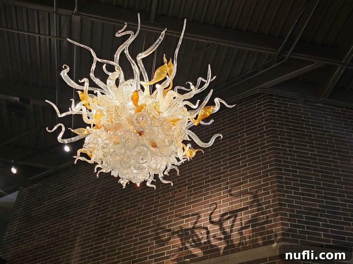 chihuly glass chandelier with reflection on the brick wall near it