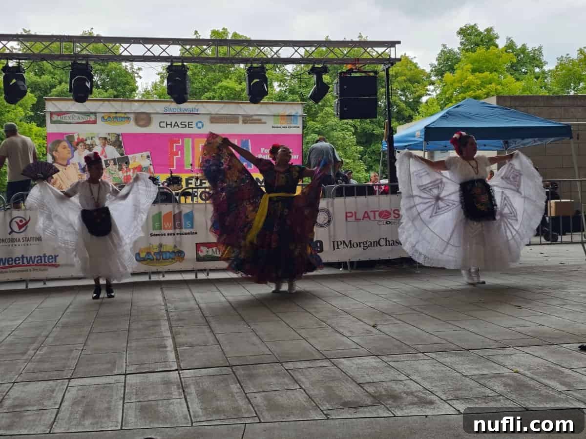 Three ladies dancing at Fiesta Fort wayne with a stage behind them.