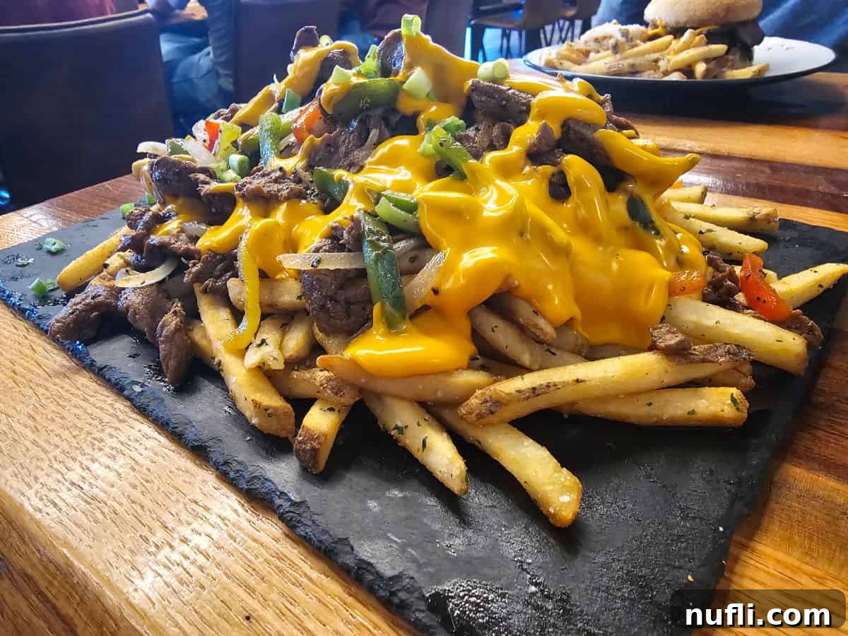 Philly cheesesteak fries on a slate platter on a table