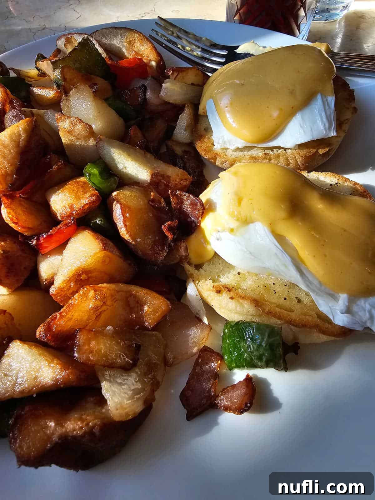 eggs benedict with potatoes on a white plate