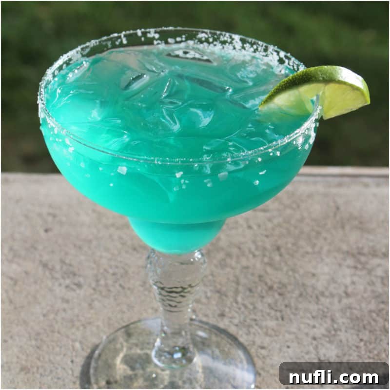 Delicious Tequila Drinks Made Easy 12 A captivating Blue Margarita in a margarita glass, adorned with a crisp lime wedge, evoking ocean hues