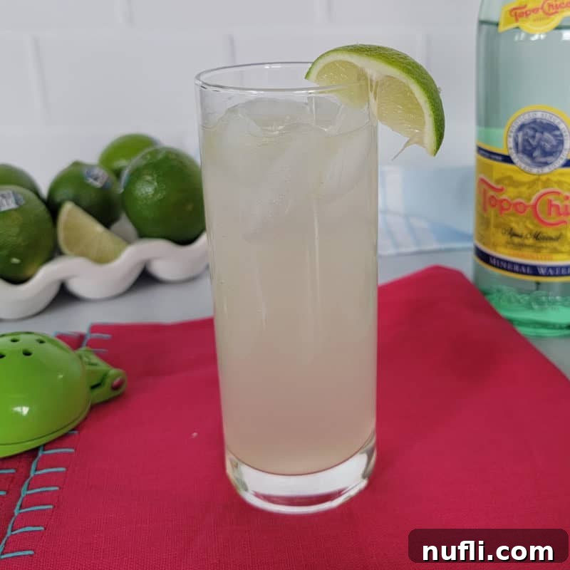 Delicious Tequila Drinks Made Easy 7 Ranch Water cocktail in a tall glass, accompanied by a stack of limes, a juicer, and a bottle of Topo Chico, highlighting its refreshing ingredients