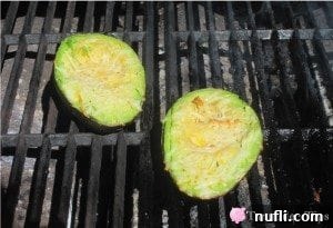 Grilled avocado halves on barbecue grates