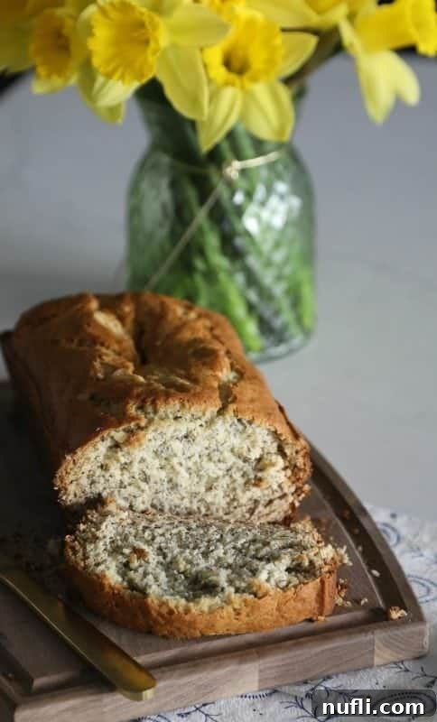 Simple Homemade Banana Bread Bliss 3 Thick slices of moist banana bread on a wooden cutting board with fresh daffodils and a glass vase in the soft focus background.
