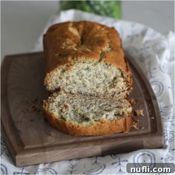 Simple Homemade Banana Bread Bliss 4 Banana bread sliced on a wood cutting board next to a cloth napkin, ready to be served.