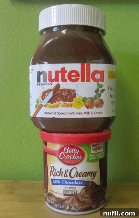 Jar of Nutella on top of a jar of milk chocolate frosting