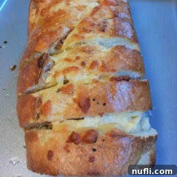 The Ultimate Garlic Bread Recipe Video 4 A close-up of cheesy garlic bread on a baking sheet, showing the golden crust and melted cheese, ready to be served.