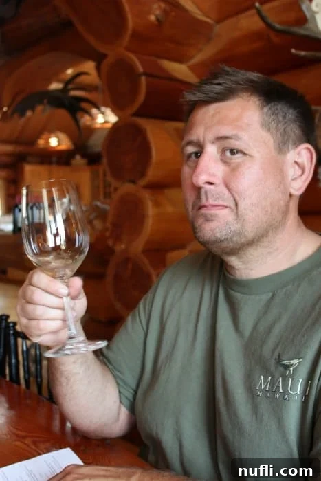 A visitor, John, holding a wine glass with a thoughtful expression during a wine tasting at Icicle Ridge Winery.
