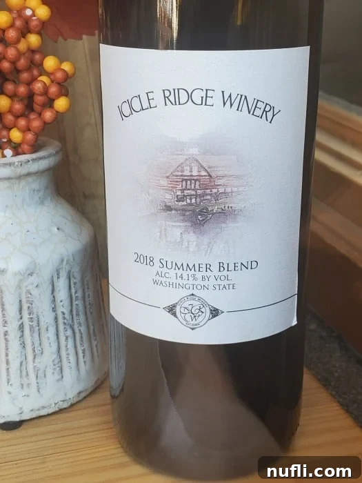 A bottle of Icicle Ridge Winery's Razzamatazz Raspberry wine, featuring its distinctive label, set against a rustic background.