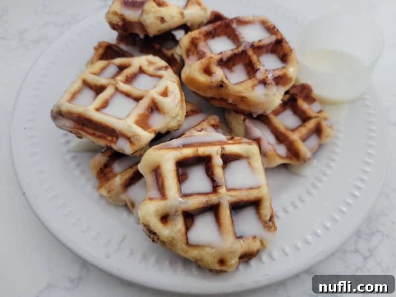 cinnamon roll waffles on a white plate covered in icing