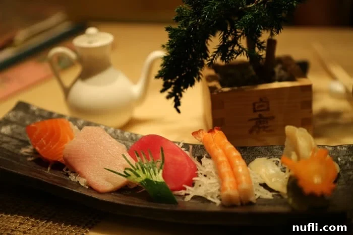 Platter of fresh sushi and sashimi presented artfully next to a bonsai plant