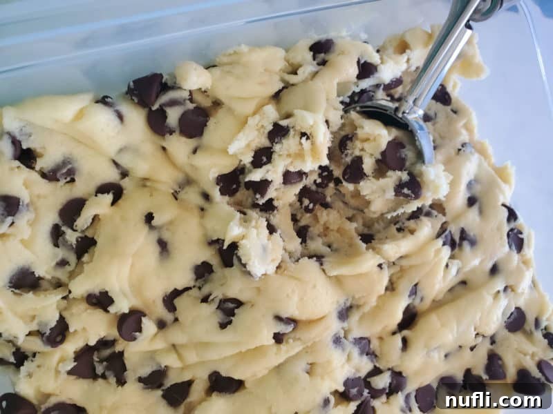 Easy Cake Mix Chocolate Chip Cookies 4 A cookie scoop carefully placing chocolate chip cake mix cookie dough onto a baking sheet, ready for the oven.