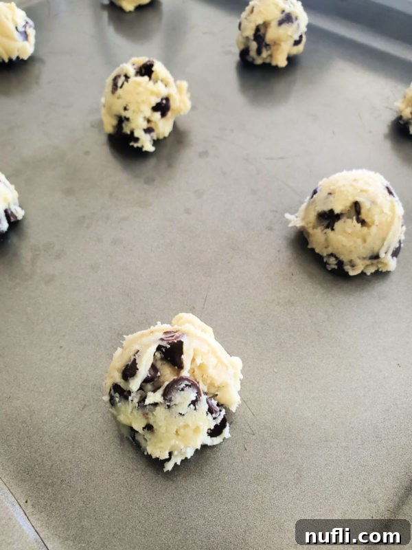 Easy Cake Mix Chocolate Chip Cookies 5 Perfectly formed chocolate chip cake mix cookie dough balls arranged on a metal baking sheet, ready for chilling and baking.